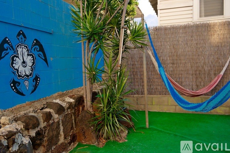 A blue wall with a white flower design and a hammock.