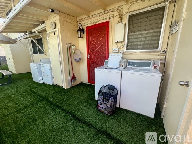 A small laundry room with a red door and a washing machine.