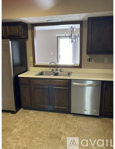A kitchen with a sink, dishwasher and refrigerator.