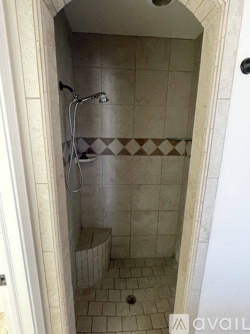 A shower with a tiled floor and a bench seat.