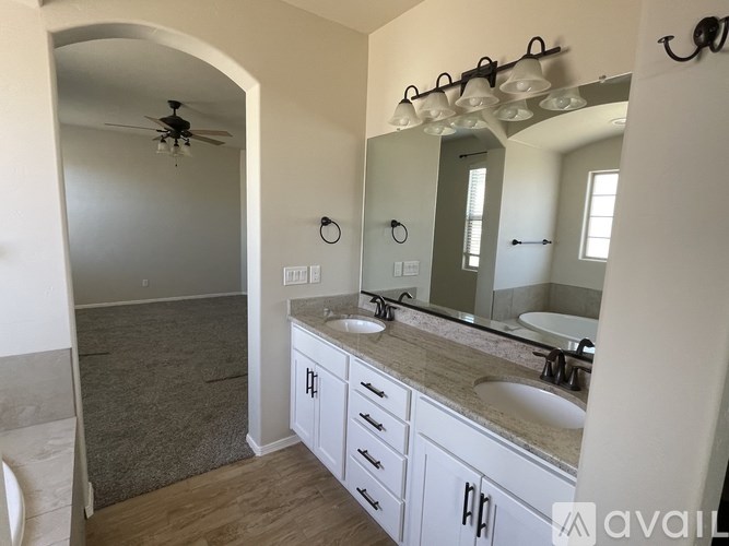 A bathroom with a vanity, sink, mirror, and a fan.