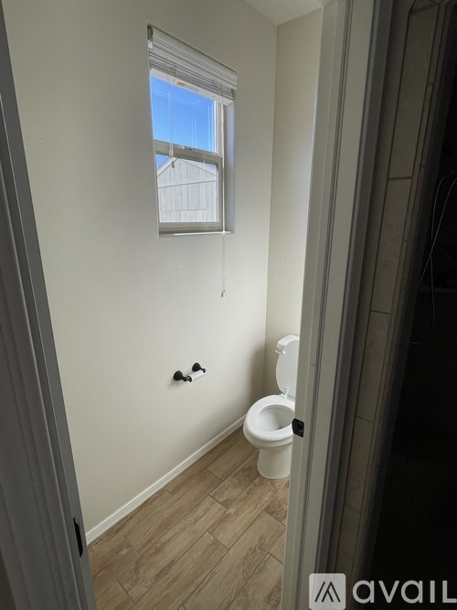 A bathroom with a toilet and a window.