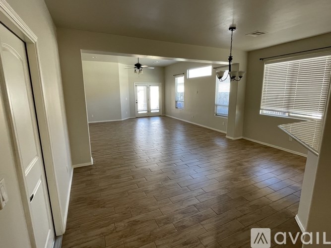 A spacious room with wooden flooring and white walls.