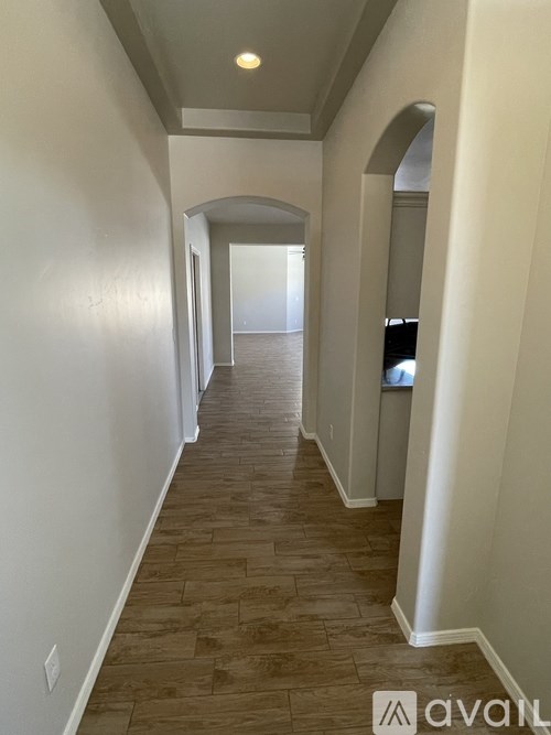 A long hallway with wood flooring and white walls.