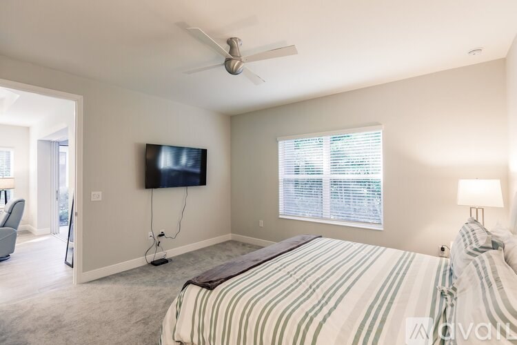 A bedroom with a bed, a television, and a ceiling fan.