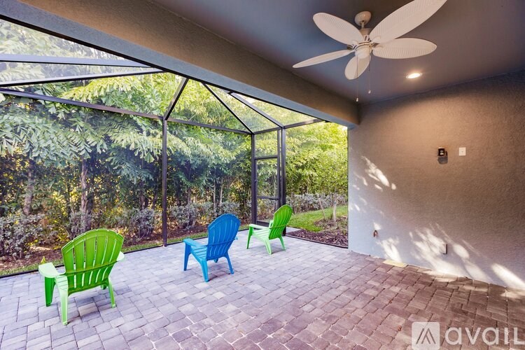 A patio with a ceiling fan and three chairs.
