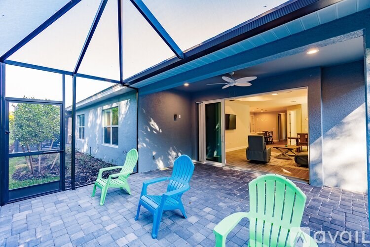 A patio with a blue and green chairs and a ceiling fan.