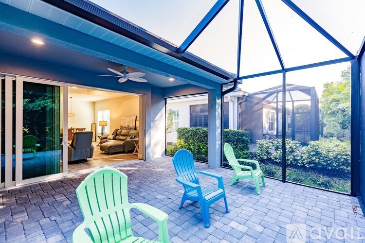 A patio with a blue and green chairs and a ceiling fan.