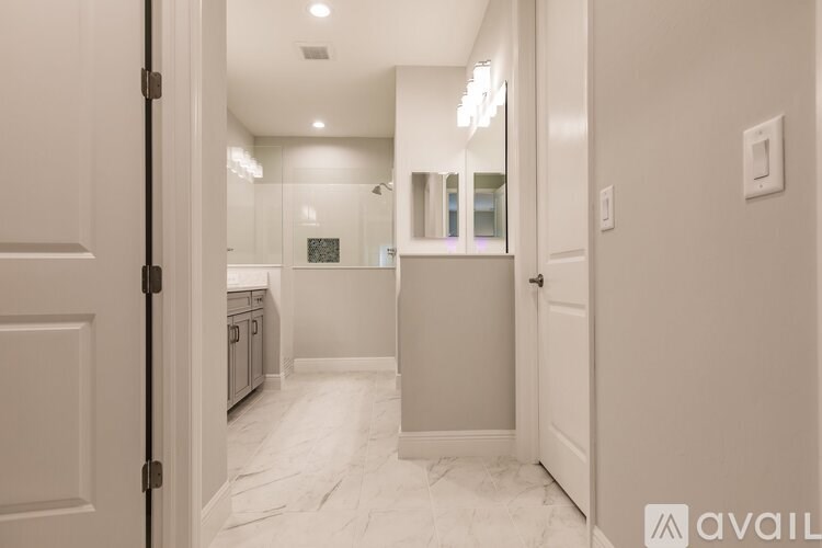 A hallway with a marble floor and a mirrored wall.