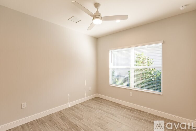 A room with a ceiling fan and a window with blinds.