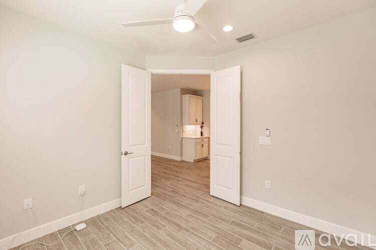 A room with a white door and a fan on the ceiling.