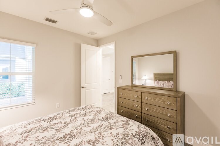 A bedroom with a bed, dresser, mirror, and window.