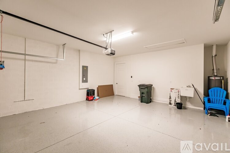 A large empty room with a blue chair and a trash can.