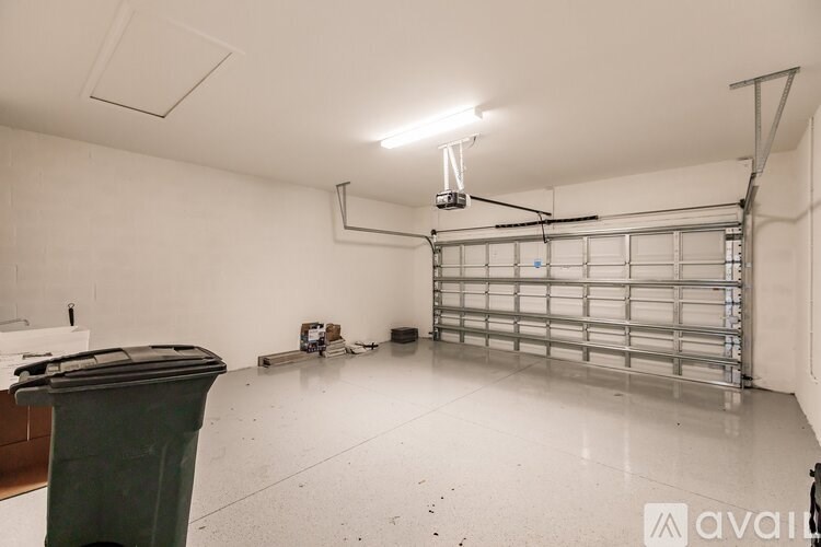 A large empty room with a green trash bin and a metal shelving unit.