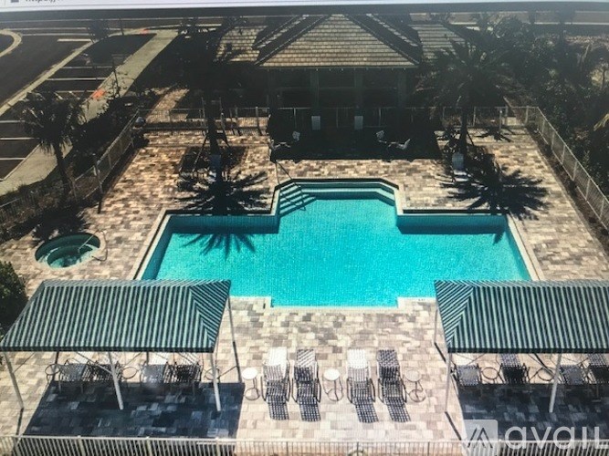 A pool surrounded by palm trees and lounge chairs.