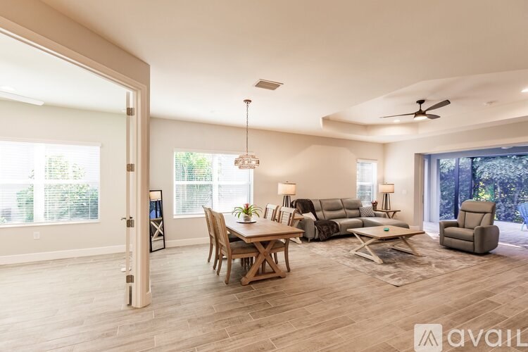 A spacious living room with a dining table and chairs, a couch, and a ceiling fan.