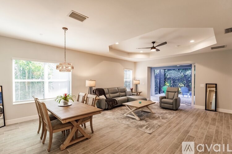 A living room with a wooden table and chairs, a couch, a coffee table, and a ceiling fan.