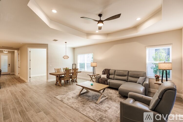 A spacious living room with a grey sofa, wooden coffee table, and a ceiling fan.