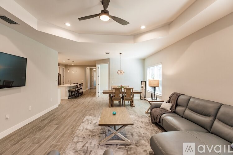 A living room with a wooden floor and a large flat screen TV mounted on the wall.