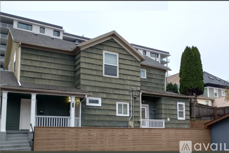 A two-story house with a balcony and a tree in front.