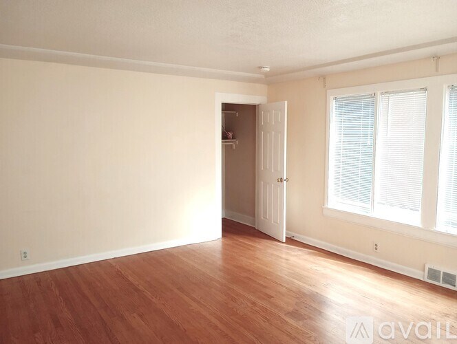 A room with wooden floors and a doorway leading to another room.