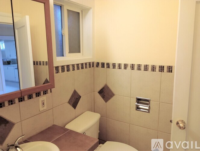 A bathroom with a toilet, sink, and mirror.