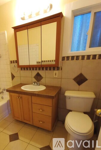 A bathroom with a toilet, sink, and cabinet.