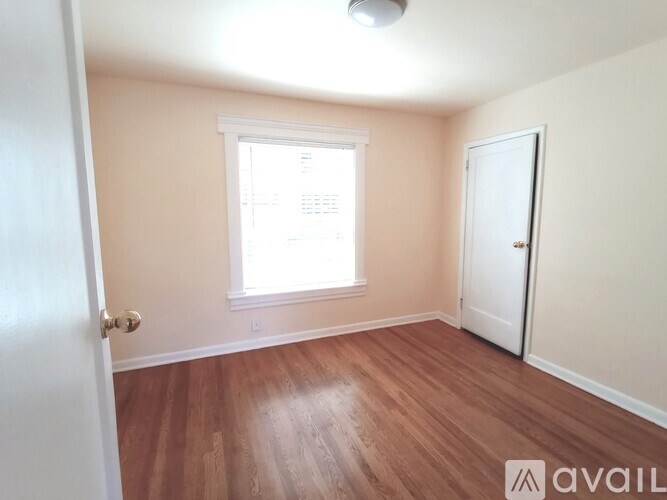 A room with wooden floors and a window with blinds.