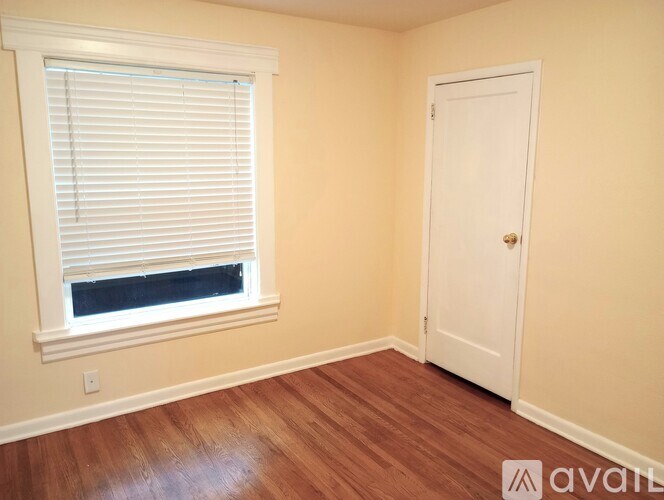 A room with a white door and a window with blinds.