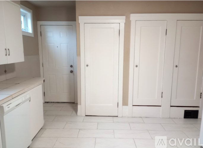 A white door is in the middle of two white cabinets.