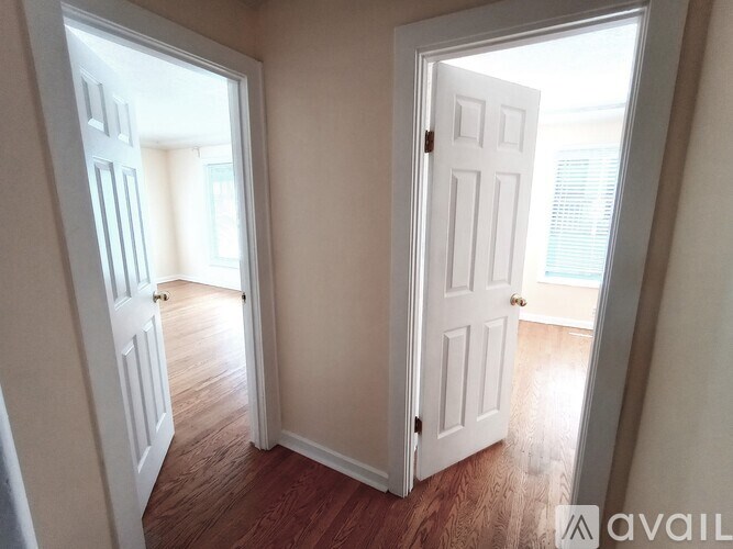 A room with two white doors, one open, with wooden flooring.