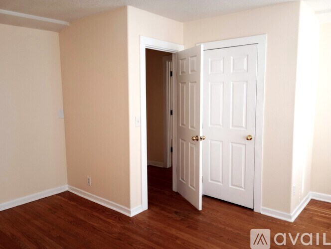 A room with a white door and wooden flooring.