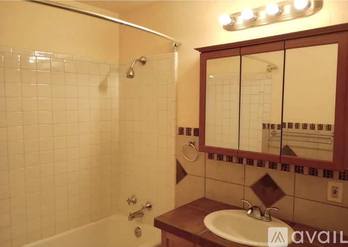A bathroom with a white tiled shower and a white sink.