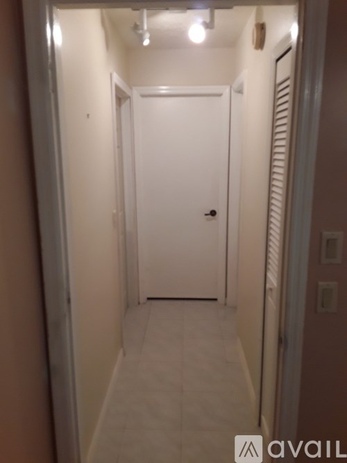 A hallway with a white door and a white wall.