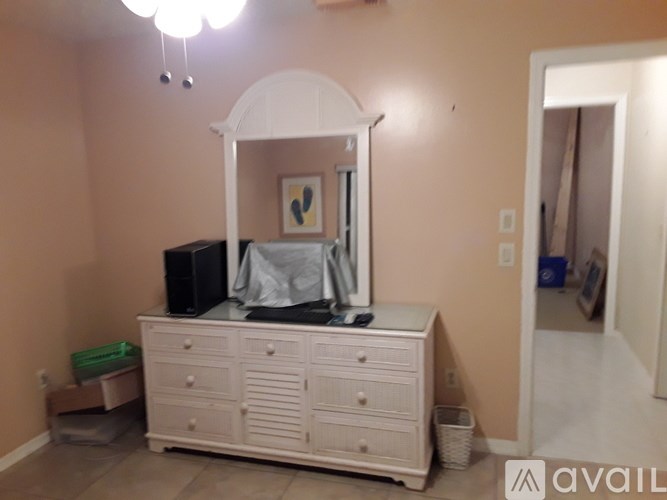 A white vanity with a mirror and a black box is in a room.
