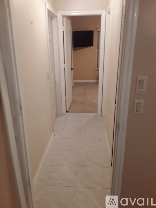 A hallway with a white tile floor and a door on the left.