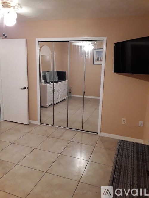 A room with a white door and a black TV mounted on the wall.
