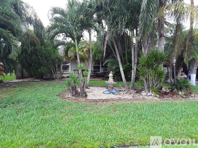 A garden with a statue surrounded by palm trees.