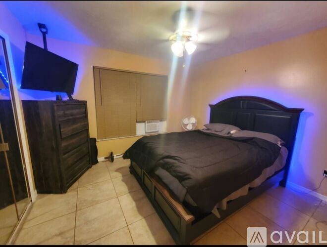 A bedroom with a bed, dresser, and ceiling fan.