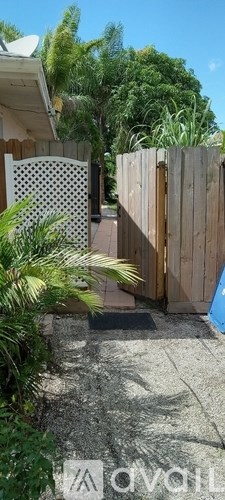 A wooden fence with a gate in the middle of a concrete path.
