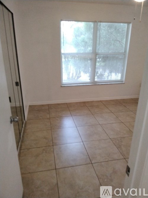 A room with a tiled floor and a window with blinds.