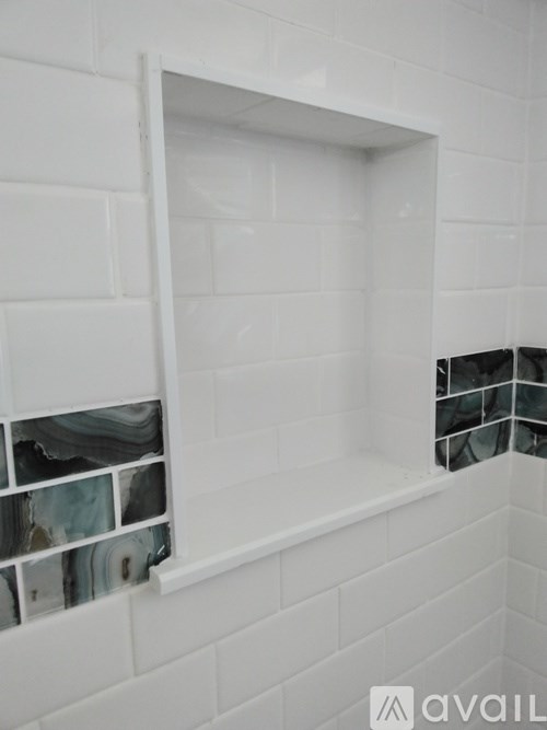 A white tiled shower with a glass block inset.