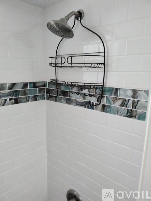 A shower head mounted on a wall with a rack below it.