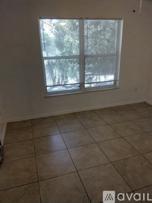 A room with a tiled floor and a window with blinds.