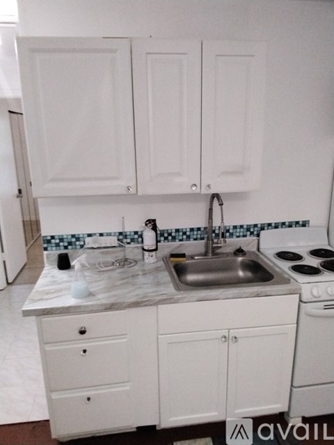 A kitchen with white cabinets and a marble countertop.