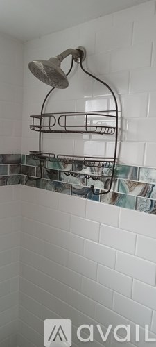 A shower head mounted on a wall with a rack below it.