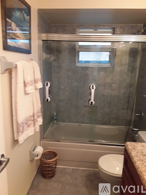 A bathroom with a glass shower door and a towel hanging on the wall.