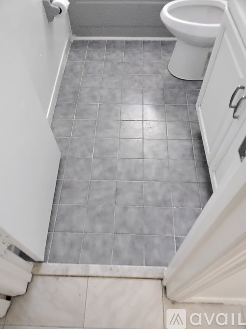 A white toilet in a bathroom with grey tiled floors.