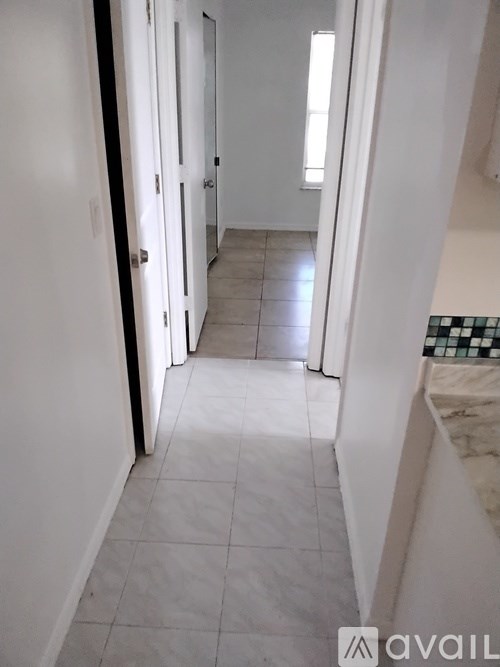 A hallway with white walls and tile flooring.