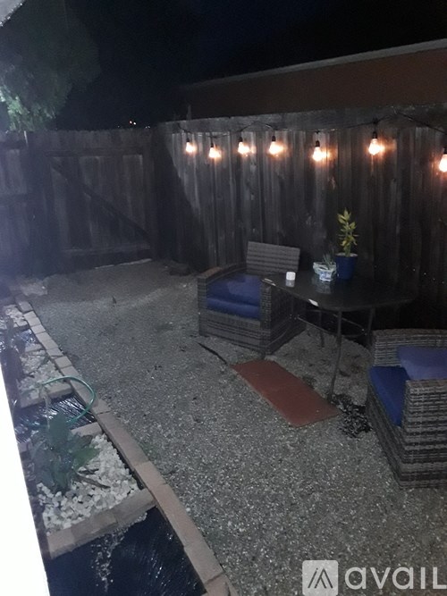 A backyard with a table and chairs under string lights.